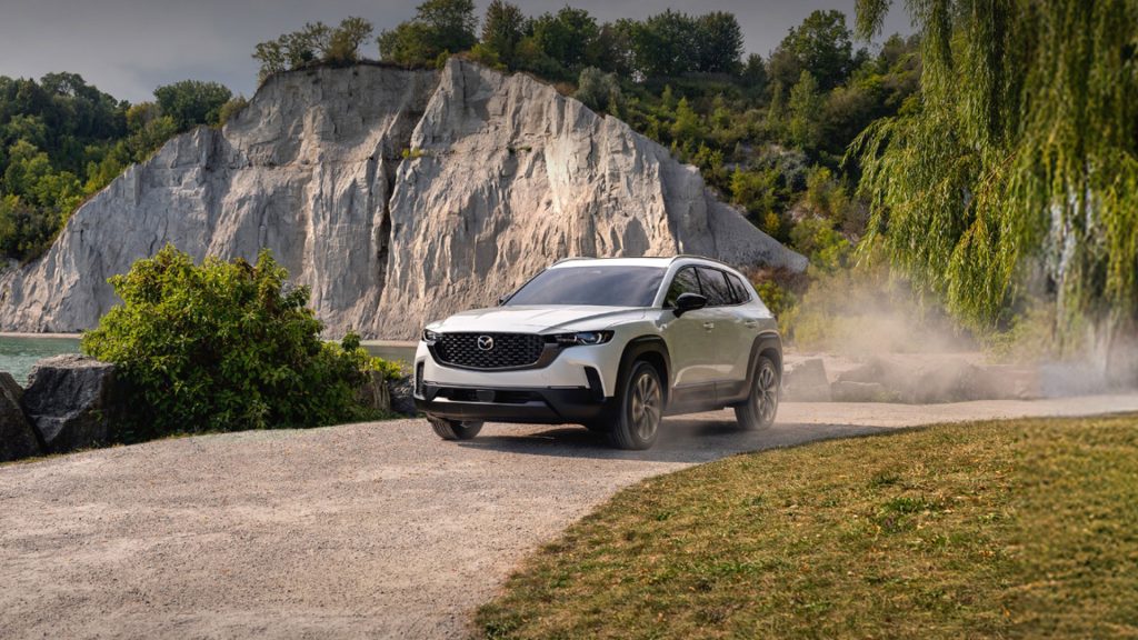 2026 Mazda CX-50 Hybrid on a road near rocky cliffs.